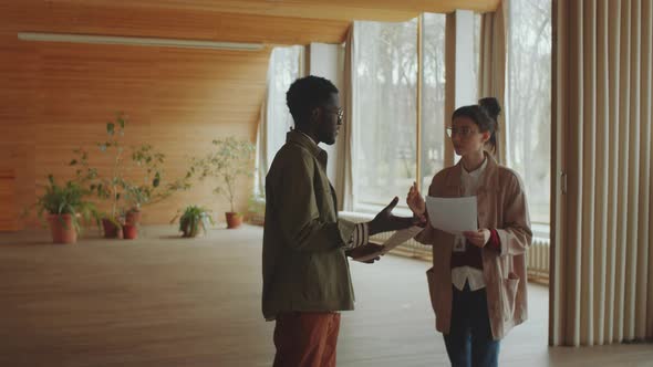 Multiethnic Colleagues Discussing Documents in Library Auditorium alt