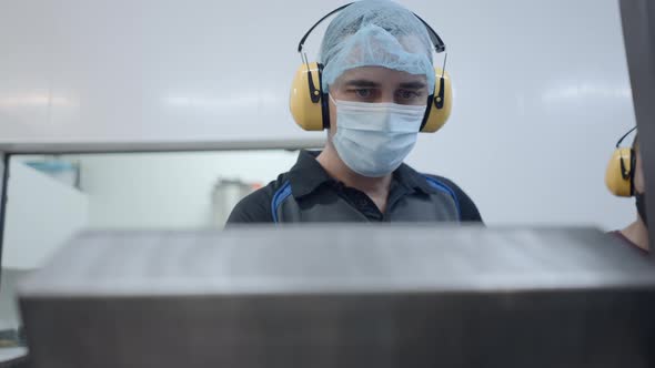 Male Worker In Mask Hairnet And Headphones During Operation In A Beer Factory alt
