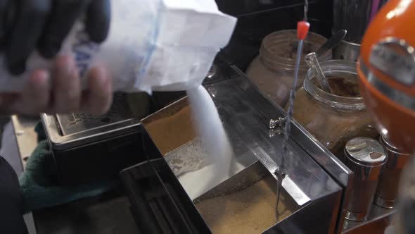 Barista pouring sugar filling stainless steal container alt