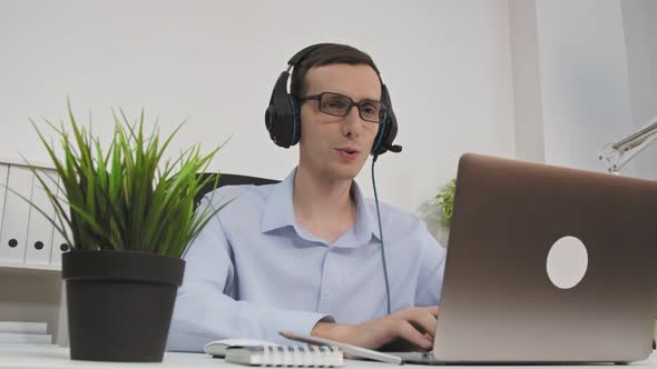 Friendly Professional Call Center Agent Wear Wireless Headset Making Conference Video Call on Laptop alt