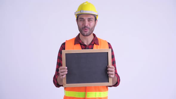 Happy Bearded Persian Man Construction Worker Talking While Holding Blackboard alt