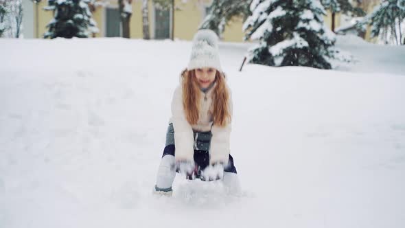 Beautiful smiling girl throwing white snow up and looking at camera in winter. alt