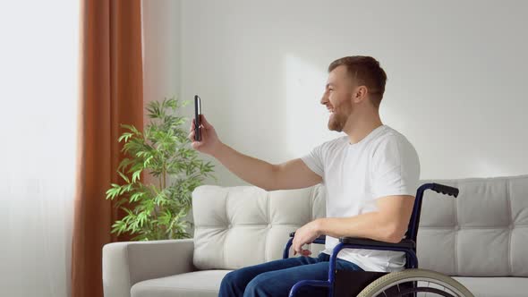 Happy Disabled Man Sitting on Wheelchair and Talking on Video Chat alt