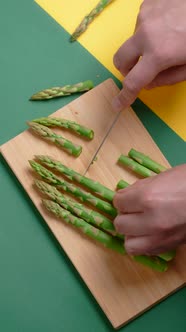 Vertical Flat Lay Video the Cook Cuts Raw Asparagus on the Wooden Board