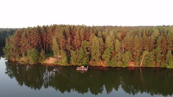 Pine Forest in the Rays of the Setting Sun with Houses Surrounded By Trees on the Shore of the Lake