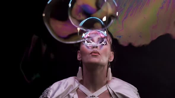 CU, Slow Motion: Tricks with Soap Bubbles. A Girl Blows a Lot of Bubbles Towards the Viewer alt