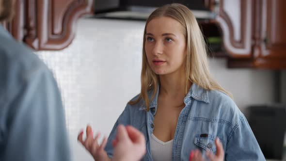 Portrait of Dissatisfied Angry Young Beautiful Woman Talking with Man in Kitchen at Home alt