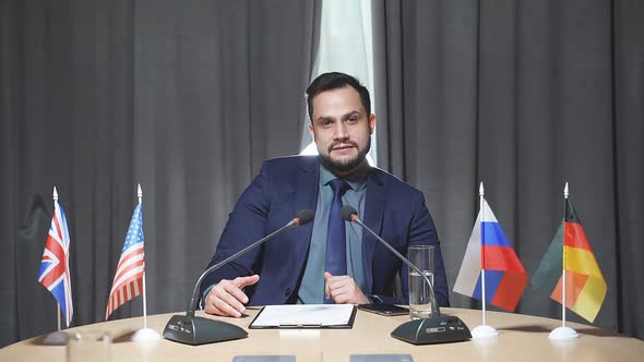 Confident Caucasian Businessman Sit Speaking Into the Microphone at Meeting