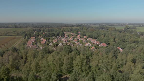 Aerial closing in on a recreational bungalow park in The Netherlands that sits inside a forest showi alt