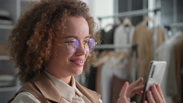 Smiling Cute Young Woman Wearing Glasses Taps Mobile Phone While Selling Goods Online on Social alt