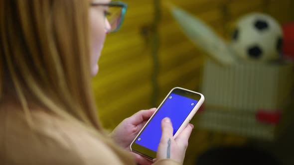 Smartphone with Blue Screen in Tattooed Female Young Hands Indoors alt