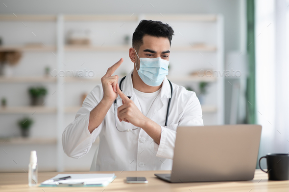 Arab doctor in face mask having video chat with patient - Stock Photo - Images