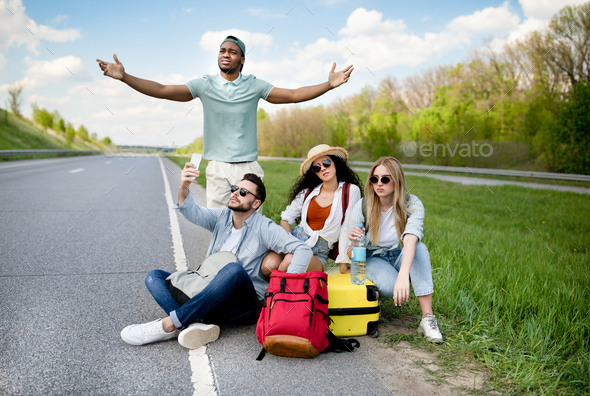 Unhappy millennial tourists sitting on roadside, cannot catch car, waiting for too long, having no
