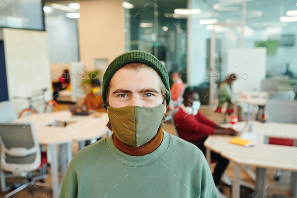 Bearded male office manager with bicycle looking at you while standing by desk - Stock Photo - Images
