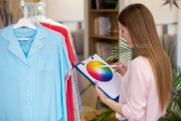 Designer girl looking at a color palette, tearing it in her hand.