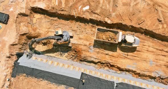 Bulldozer is Scraping a Layer of Soil and Excavator is Digging and Dumping Earth for Loading Onto alt