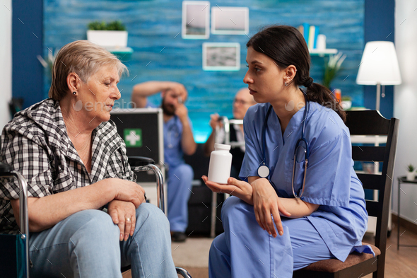 Assistant woman helper explaining pills treatment discussing with senior elder person
