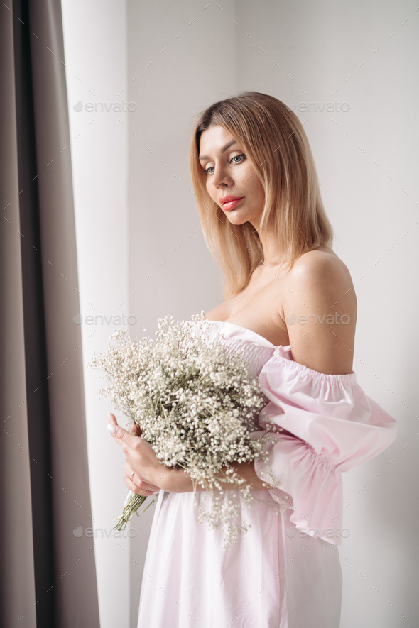 Pretty smiling young woman standing with a bouquet of flowers - Stock Photo - Images