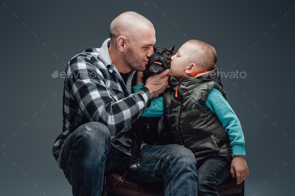 Father and son kissing their cheerful dog