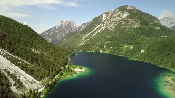 Aerial view of Lago del Predil lake surrounded by hills in Itally. alt