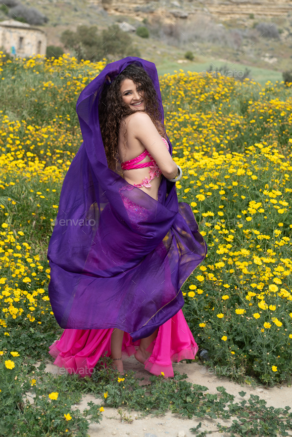 Woman performing belly oriental dancing wearing coloured costume. Outdoors dancing