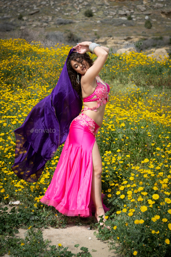 Woman performing belly oriental dancing wearing coloured costume. Outdoors dancing