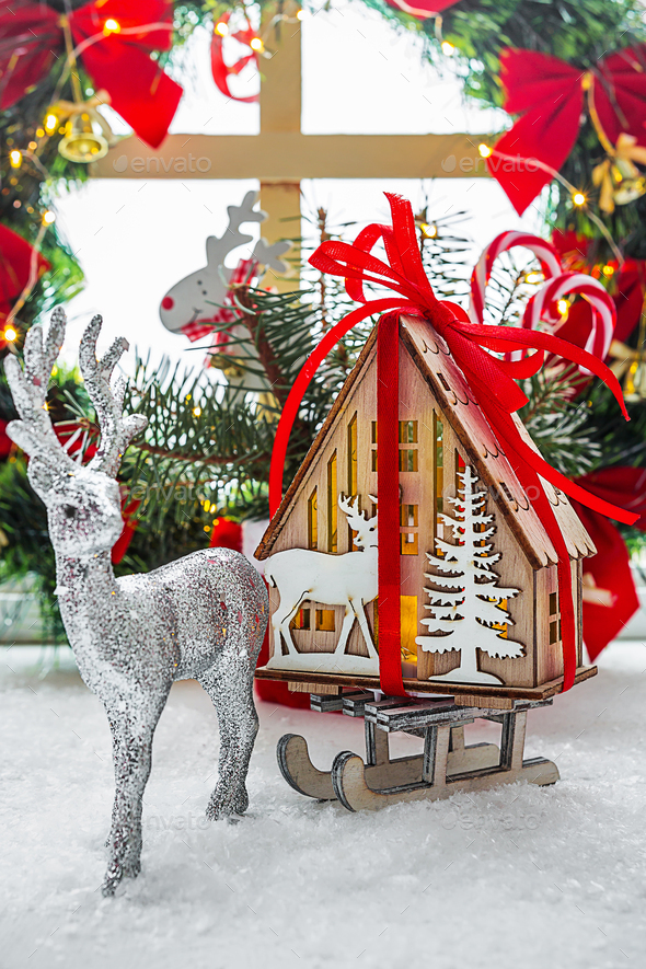 Christmas decor: deer carries on a sleigh a gift dream house. Comfort, candles, Christmas wreath on