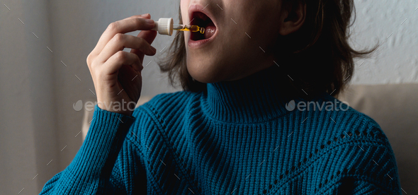 Woman taking cbd oil under tongue - Alternative medicine concept - Focus on dropper