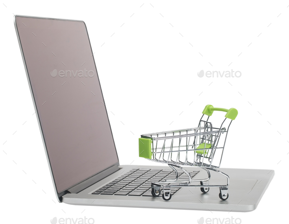 Laptop and toy metal shopping trolley on white background isolate