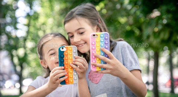 Little Girls Use Phones In Trendy Cases For Anti Stress Pop It Stock Photo By Puhimec