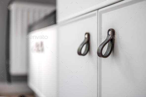 Close-up of black knobs on a white cabinet.