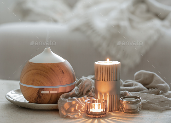 Cozy home composition with air humidifier and candles on blurred background.  Stock Photo by puhimec