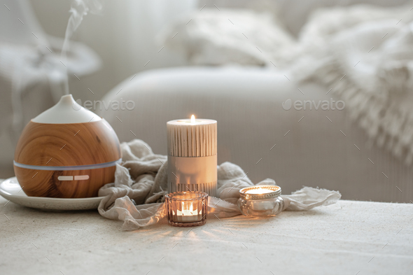 Cozy home composition with air humidifier and candles on blurred background.  Stock Photo by puhimec