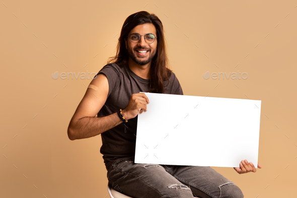 Handsome middle-eastern guy got vaccinated, holding blank board