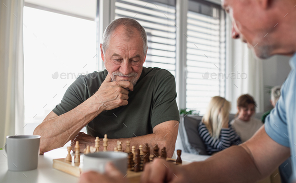Group of senior friends playing board games indoors, party and social gathering concept