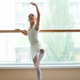Ballerina in ballet pointe shoes stretches on barre. Woman