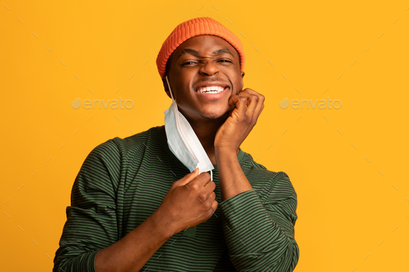 Itchy Skin. Irritated Young Black Guy Scratching Face After Wearing Medical Mask