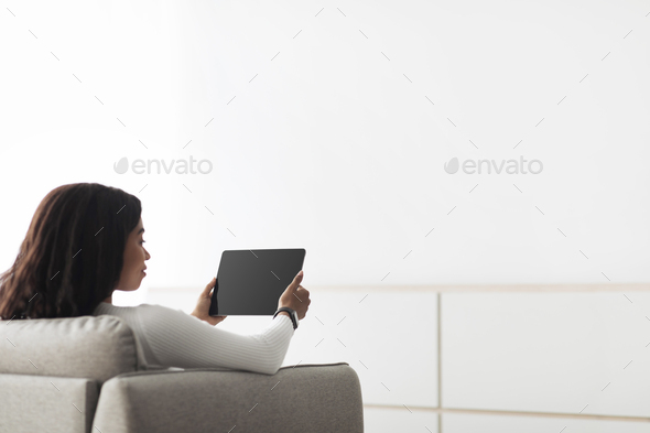 African american woman controlling smart home devices using digital tablet with blank black screen