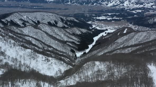 aerial of mountain landscape during winter in Nozawa Onsen Ski Resort in Japan alt