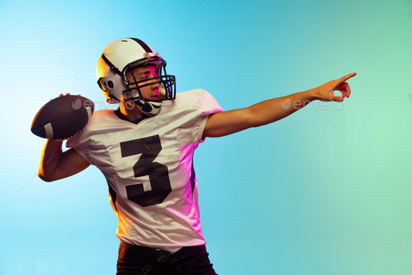 Portrait of American football player training isolated on blue studio background in neon light