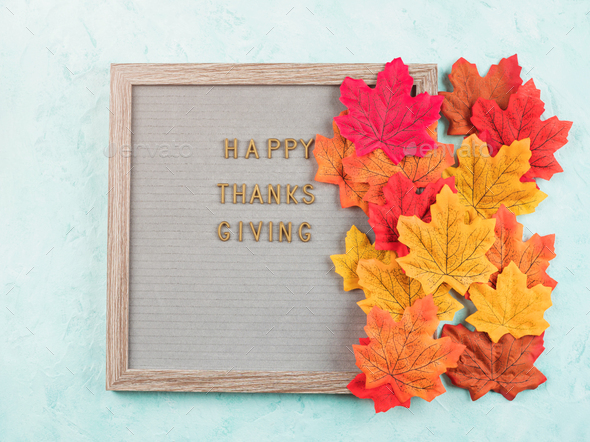 Happy thanksgiving greetings on letter board with autumn red and orange leaves.