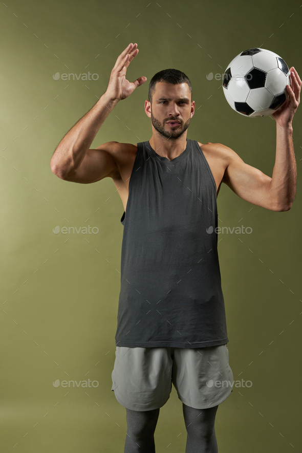 Adult Caucasian handsome football trainer in action with ball in the indoors