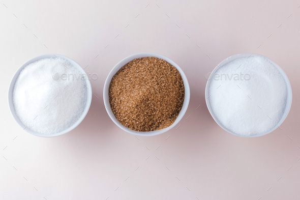 White sugar, cane sugar and sugar substitute in bowls top view.
