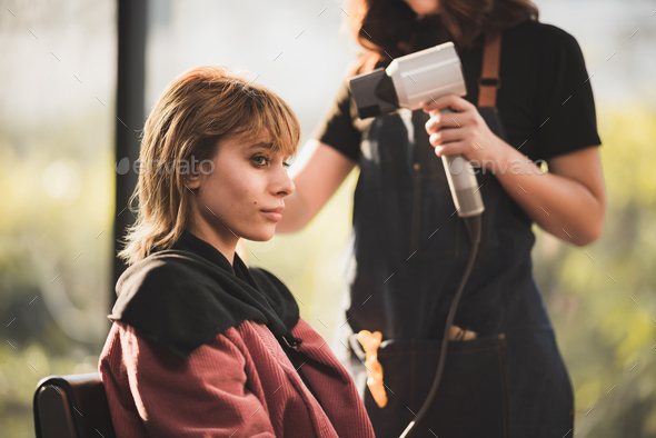 hairstylist drying hair and blowdrying hair to beautiful short bond ...