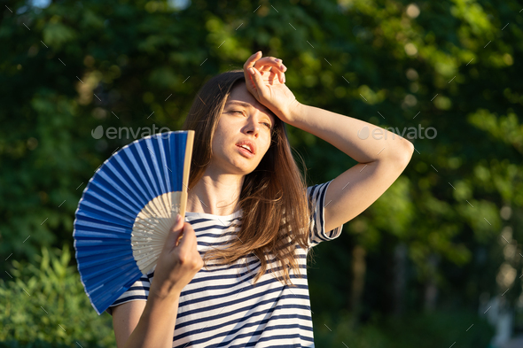 Young woman suffer heatstroke outdoors. Unhappy girl feel bad of hot temperature touch forehead