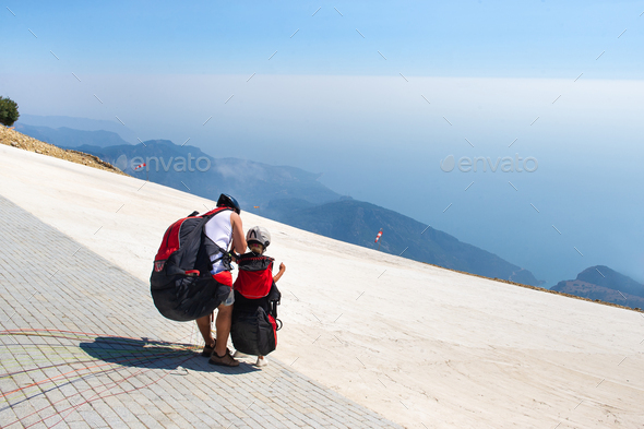 A little girl with an instructor in paragliding gear is preparing for a flight from Mount Babadag