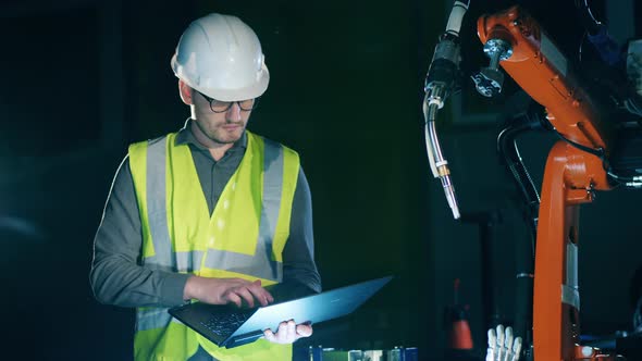Male Engineer Is Managing a Robotic Device with the Laptop alt