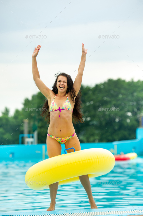 a woman in a bikini with a rubber inflatable circle playing and having a good time in the amusement