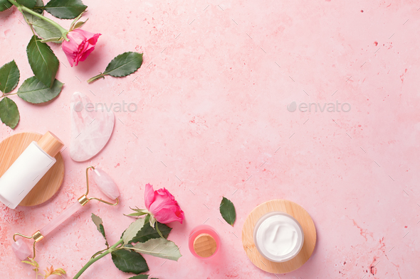 Assortment of plant based beauty products with rose oil or rose extract on pink