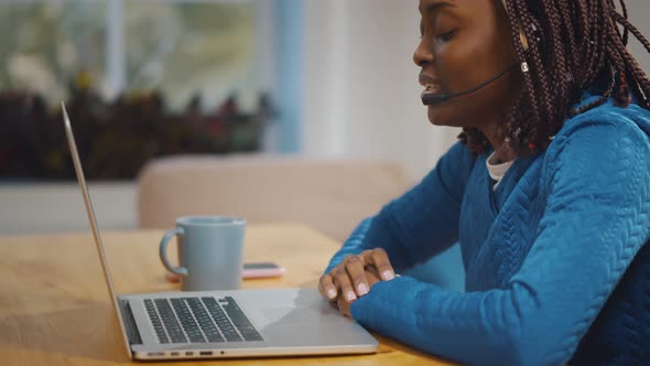 Young African Woman Using Headset and Laptop for Online Communication alt
